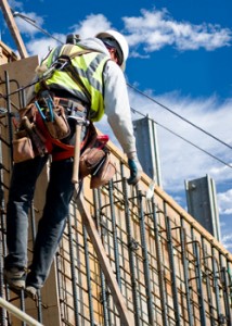 A construction worker on a high wall against a cloudy sky.